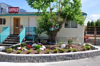 a garden in front of a building with a tree at Canadas Best Value Inn Mile-0-Motel Lillooet in Lillooet