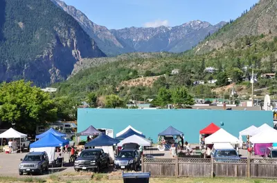a group of cars parked in a parking lot with mountains in the background at Canadas Best Value Inn Mile-0-Motel Lillooet in Lillooet