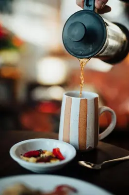 a person is pouring coffee into a coffee cup at A Bear and Bison Country Inn in Canmore