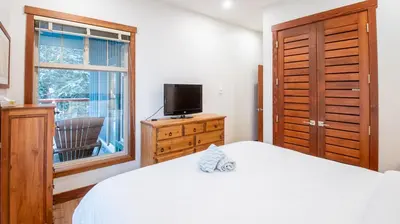 a bedroom with a bed and a television and a window at Snow Creek Lodge by Fernie Lodging Co in Fernie