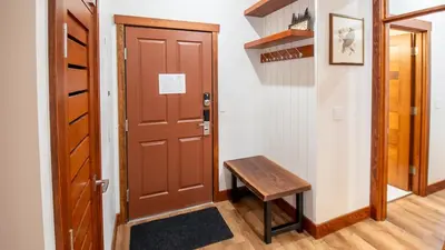 a hallway with a wooden door and a wooden bench at Snow Creek Lodge by Fernie Lodging Co in Fernie