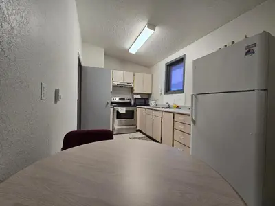 a kitchen with a table and a refrigerator at Alpine Inn in Valemount