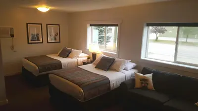 a bedroom with two beds and a couch and a window at Snow Valley Lodging in Fernie