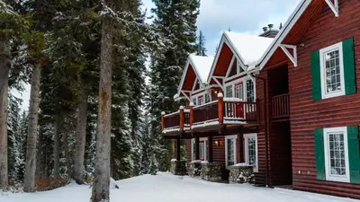 a log home with a deck in the snow at Paradise Lodge and Bungalows in Lake Louise