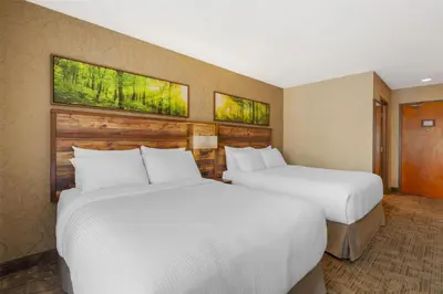 two beds in a hotel room with two windows at Best Western Plus Valemount Inn & Suites in Valemount