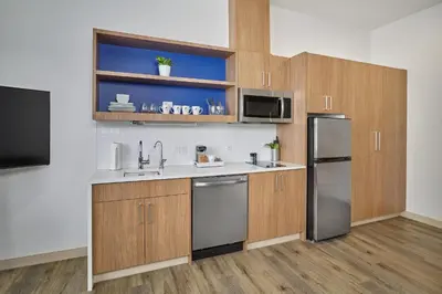 a kitchen with wooden cabinets and a stainless steel refrigerator at Element Edmonton West in Edmonton
