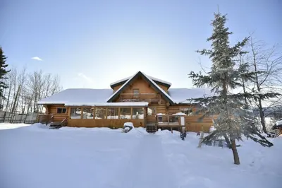 a log cabin in the snow with a tree at Inn on the Lake - Whitehorse in Marsh Lake