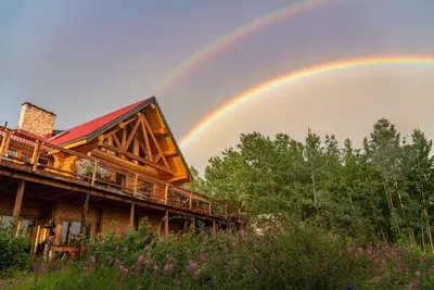 a rainbow in the sky above a house at Inn on the Lake - Whitehorse in Marsh Lake
