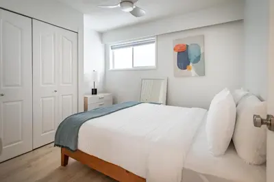 a white bedroom with a bed and a window at Okanagan Lakefront Resort in Penticton