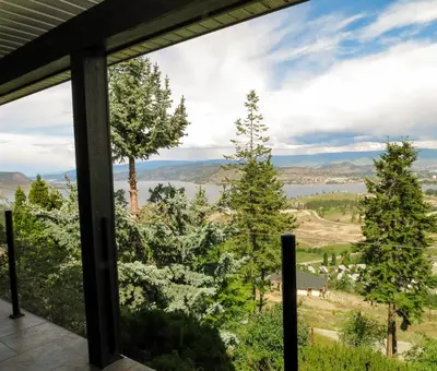 a view from the porch of a house with trees at A View of the Lake B & B in West Kelowna
