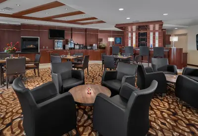a hotel lobby with chairs and tables and a bar at Metterra Hotel on Whyte in Edmonton