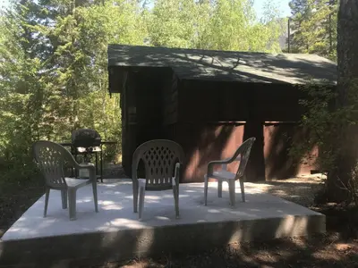 three chairs and a grill in front of a cabin at Addison's Bungalows in Brisco