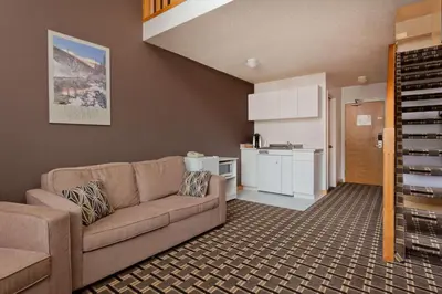 a living room with a couch and a kitchen at Super 8 by Wyndham Valemount in Valemount