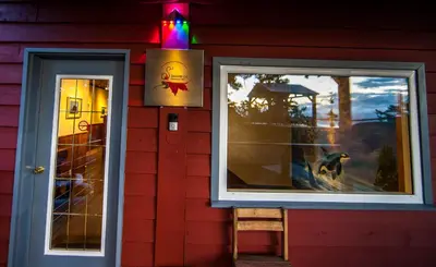 a red house with a dog sitting outside of a window at Shangri-La Oceanfront vacation home in Pender Island