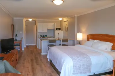 a bedroom with a large bed and a kitchen at The Waterfront Suites and Marina in Nanaimo