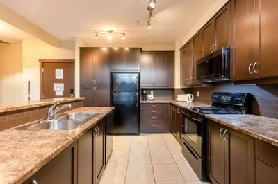 a kitchen with wooden cabinets and a stainless steel refrigerator at 2 Bedrooms Mountain Views l AC in Fernie