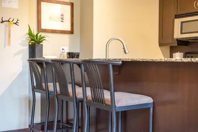 a kitchen with three bar stools at a kitchen counter at 2 Bedrooms Mountain Views l AC in Fernie