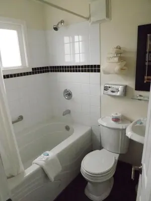 a bathroom with a toilet and a tub and a sink at Travellers Motel in Cranbrook