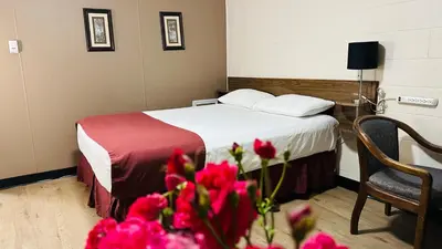 a hotel room with a bed with red flowers at Travellers Motel in Cranbrook