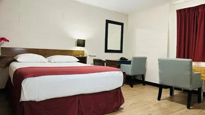 a hotel room with a bed and a desk with chairs at Travellers Motel in Cranbrook