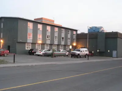 a parking lot with cars parked in front of a building at Discovery Inn in Yellowknife