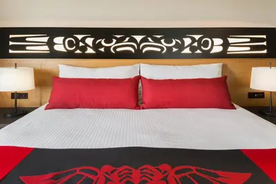 a bedroom with a bed with red pillows at Kwa'lilas Hotel in Port Hardy