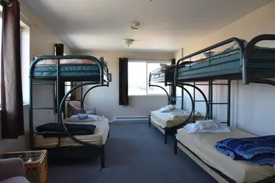 a room with three bunk beds and a window at North Coast Trail Backpackers Ltd in Port Hardy