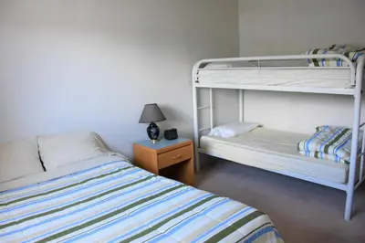 a bedroom with two bunk beds and a table with a lamp at North Coast Trail Backpackers Ltd in Port Hardy
