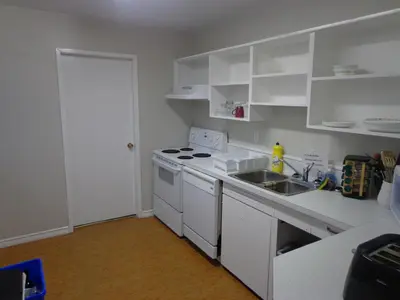 a white kitchen with a sink and a stove at North Coast Trail Backpackers Ltd in Port Hardy