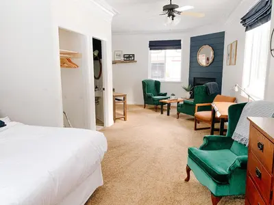 a bedroom with a bed and chairs and a desk at The Inn at the Ninth Hole Bed & Breakfast in Salmon Arm