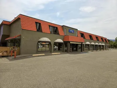 a building with a red roof on a parking lot at Motel 6 Merritt, BC in Merritt