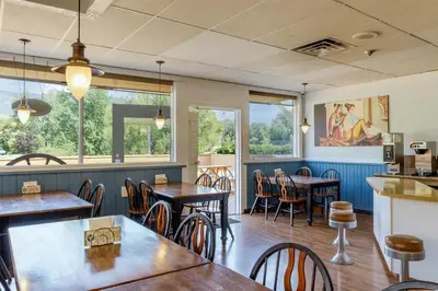 a restaurant with tables and chairs and windows at Motel 6 Merritt, BC in Merritt