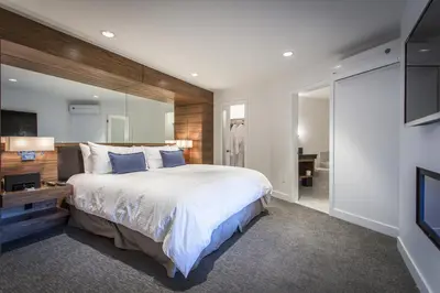 a bedroom with a large bed and a flat screen tv at Qualicum Beach Inn in Qualicum Beach