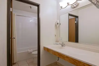 a bathroom with a sink and a toilet and a mirror at Super 8 by Wyndham Kamloops On The Hill in Kamloops