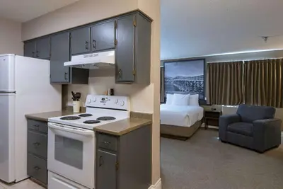a small kitchen with a bed and a kitchen with a stove at Super 8 by Wyndham Kamloops On The Hill in Kamloops