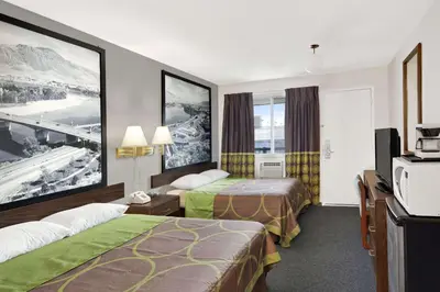 a hotel room with two beds and a tv at Super 8 by Wyndham Kamloops East in Kamloops