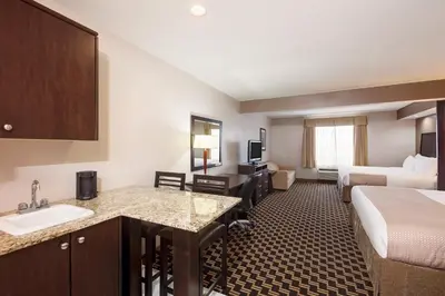 a hotel room with a sink and a bed at Ramada by Wyndham Cold Lake in Cold Lake