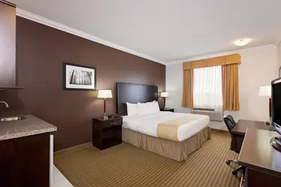 a hotel room with a bed and a desk at Ramada by Wyndham Cold Lake in Cold Lake