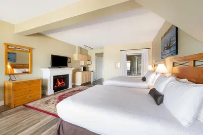 a large bedroom with two beds and a fireplace at Sidney Waterfront Inn & Suites in Sidney