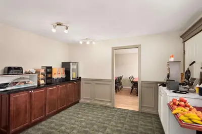 a kitchen with wooden cabinets and a table with fruit on the counter at Travelodge by Wyndham Salmon Arm BC in Salmon Arm