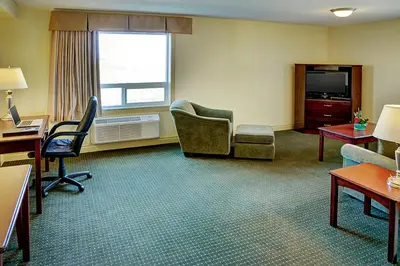 a hotel room with a desk and chairs and a television at Nova Inn Acheson in Spruce Grove