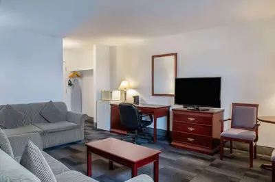 a living room with a couch a desk and a tv at Days Inn & Conference Centre by Wyndham Camrose Norsemen in Camrose
