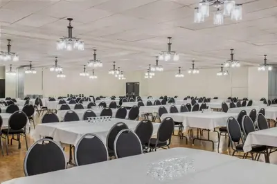 a banquet hall with white tables and chairs and chandeliers at Days Inn & Conference Centre by Wyndham Camrose Norsemen in Camrose