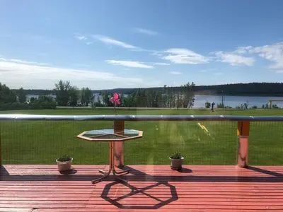 a table on a deck with a view of a field at Cariboo Log Guest House in Lac La Hache