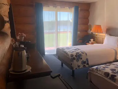 a hotel room with a bed and a window at Cariboo Log Guest House in Lac La Hache