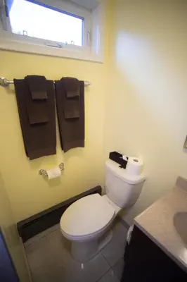 a bathroom with a toilet and a window and towels at Stardust Motel in Camrose