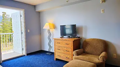 a living room with a tv and a chair at Misty Mountain Inn & Suites in Grande Cache