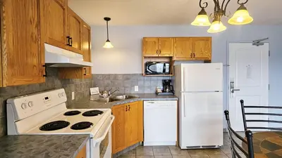 a kitchen with white appliances and wooden cabinets at Misty Mountain Inn & Suites in Grande Cache