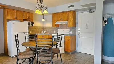 a kitchen with a table and chairs and a refrigerator at Misty Mountain Inn & Suites in Grande Cache
