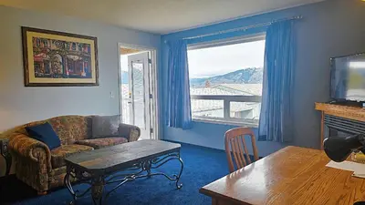 a living room with a couch and a table and a window at Misty Mountain Inn & Suites in Grande Cache